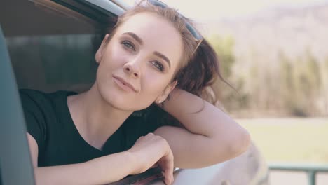 girl with long lashes and tattoo leans out of automobile