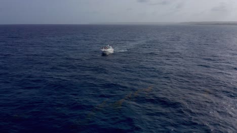 Scenic-shot-with-drone-in-open-sea-deep-blue-waters-in-Cap-Cana,-with-view-of-white-boat