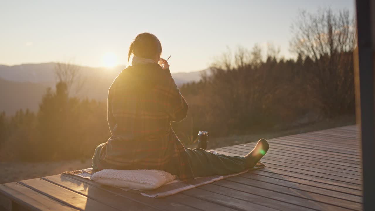 Woman enjoying sunset on a deck in the mountains
