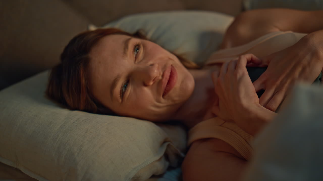 Lady watching smartphone bed looking screen with smile close up. Happy woman