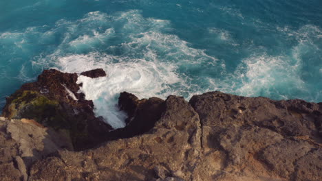 Vista-Aérea-De-Las-Olas-Del-Océano-Rompiendo-En-Las-Rocas-Hermoso-Mar-Azul-Chapoteando-En-La-Costa-Costa-Surf-4k