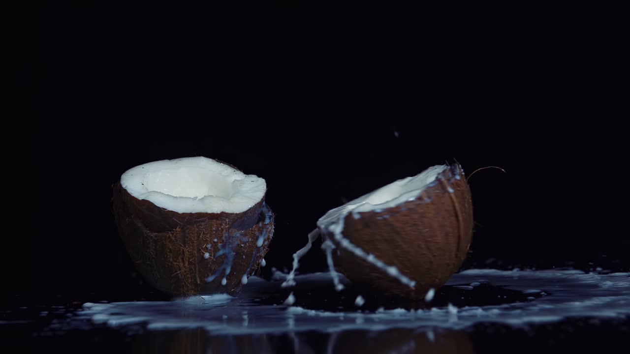 Coconut broken in slow motion on black background