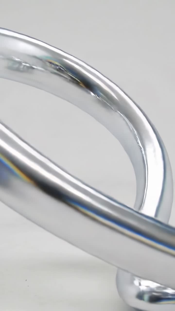 Video verticale: La telecamera si allontana rivelando un anello cromato rotante su un pavimento grigio, che mostra una lucentezza