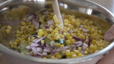 Mixing-together-vegetables-for-a-salad,-corn-with-onion-and-cucumber-close-shot