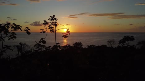 aerial drone forward movement capturing the mesmerizing uvita beach sunset in costa rica: an enchanting orange sun casting its glow upon the sea, vibrant natural beauty