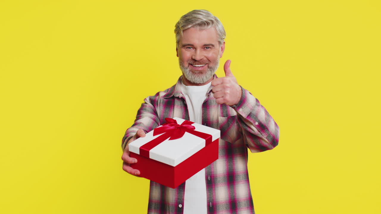 Mature man gifting box with red ribbon joyful smile gesture celebration mood birthday surprise