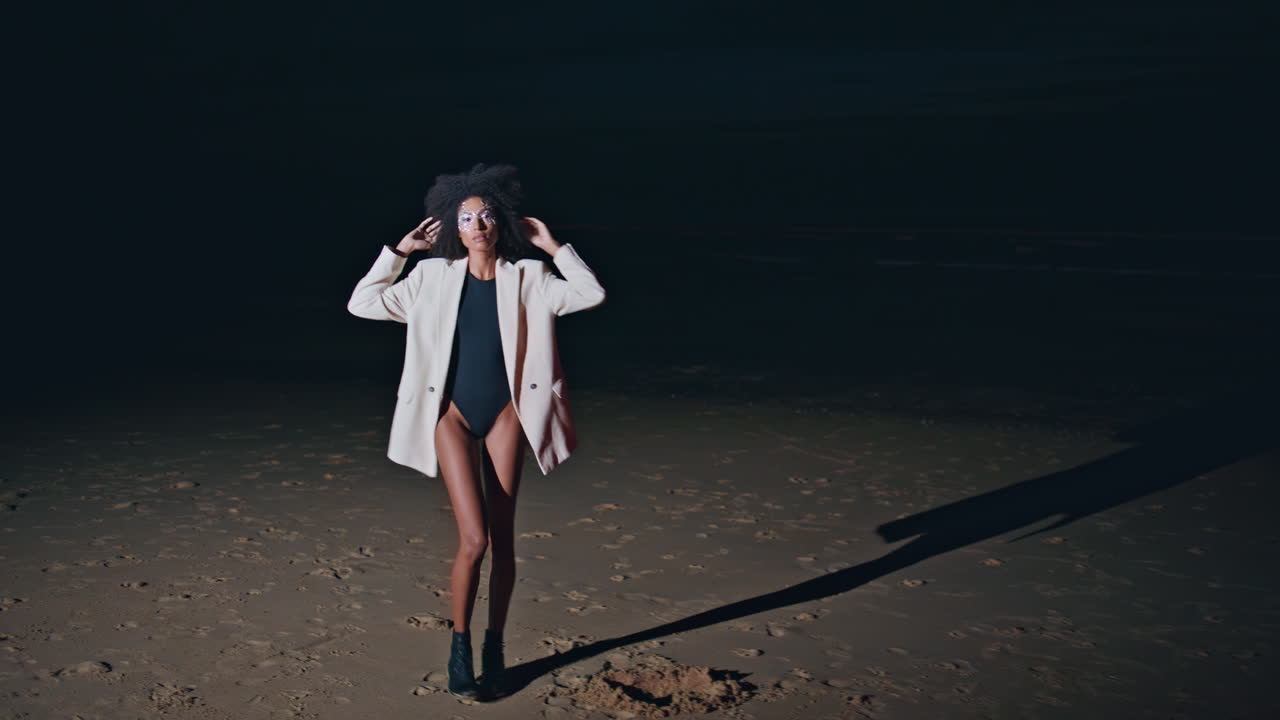 Fashionista posing dark beach in light. Trendy stylish girl in swimsuit jacket