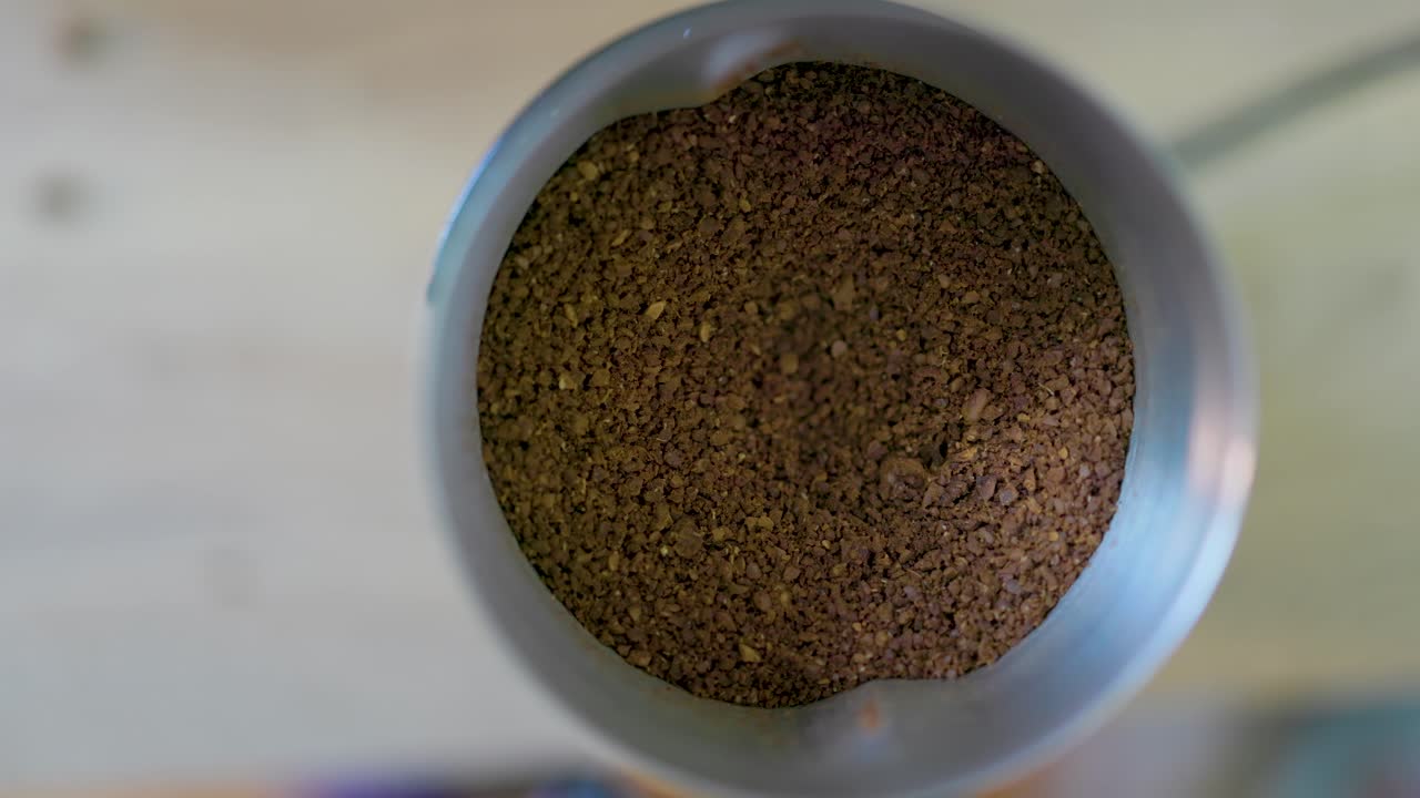 vista aérea de manos afroamericanas abrir la tapa de un molinillo de café para revelar deliciosos granos de café para una buena taza de café