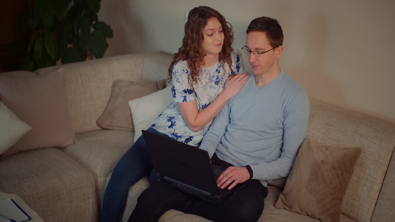 Couple using laptop on couch at home