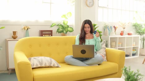 woman shopping online with credit card on laptop at home