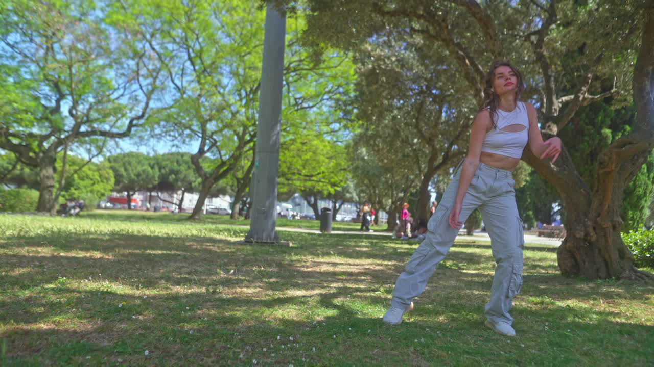 una mujer joven bailando en un parque.