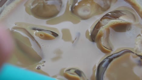 iced coffee with ice cubes and a blue straw