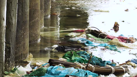 primer plano, agua del océano contaminada, basura flotando junto a los pilares del muelle