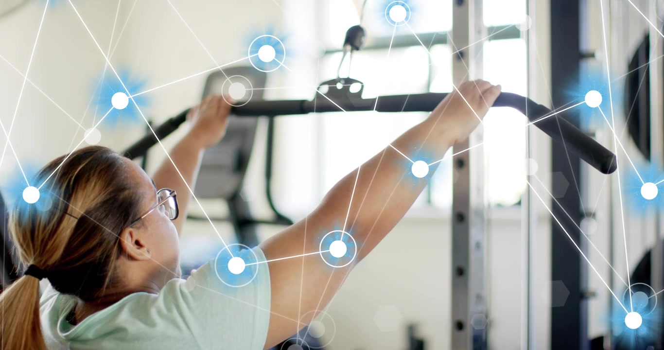 Woman at gym grasping pulldown bar initiating digital overlay while pulling and analyzing tension