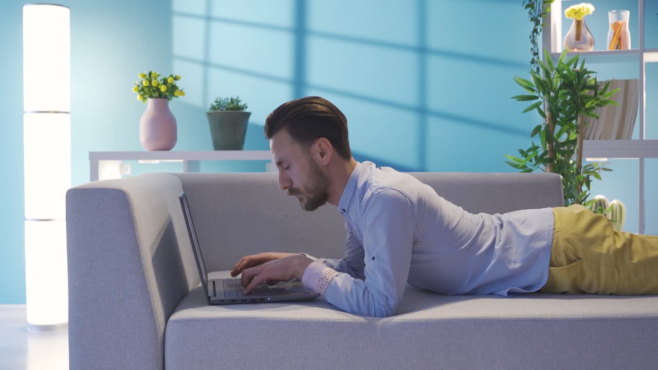 노트북을 사용하여 집에서 소파에 누워있는 우아한 사업가, 휴식하고 그의 일을하고 있습니다.