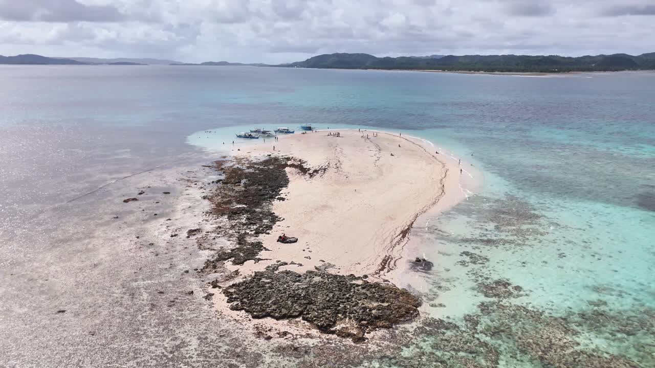 Drone view of Naked-Island or Pansukian in Siargao, Philippines, showing its white sandbar, surrounding coral reefs, and the clear shallow waters of the Pacific Ocean with distant coastlines