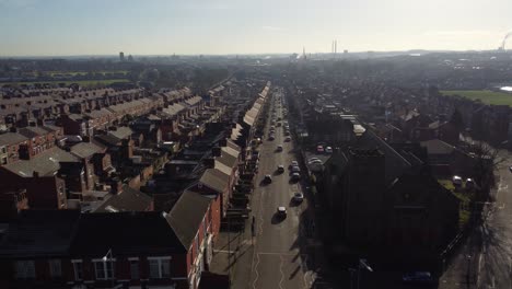 Vista-Aérea-A-Través-De-Casas-Adosadas-Y-Un-Largo-Camino-Que-Conduce-Hacia-El-Bullicioso-Centro-De-La-Ciudad,-Estableciendo-Una-Escena-Callejera