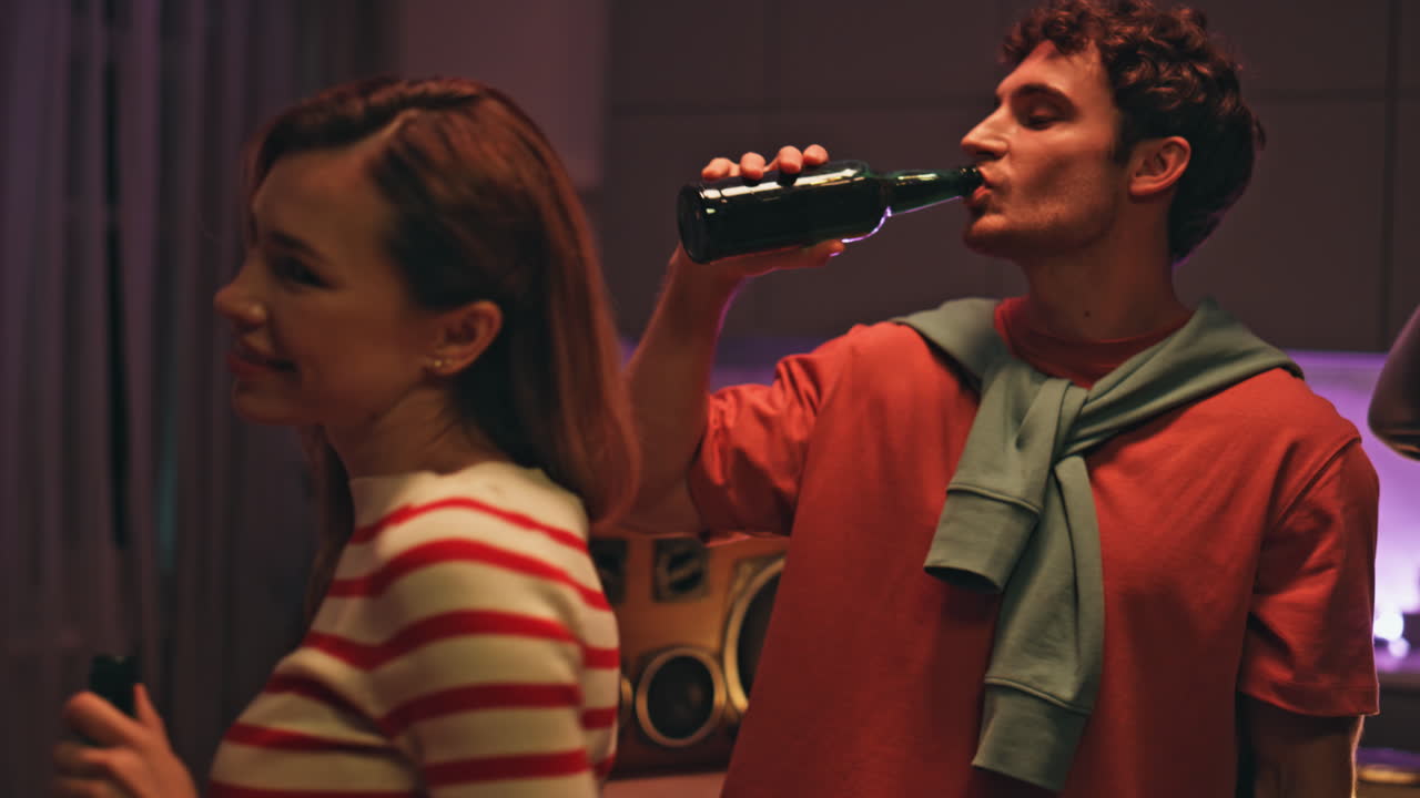 Partying people drinking beer at night hangout at home closeup. Friends clinking