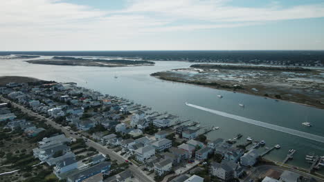 Wide-aerial-tracking-speedboat-in-distance-Wrightsville-Beach,-North-Carolina