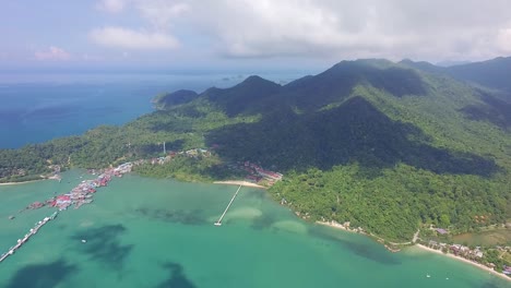 toma aérea lateral de un muelle turístico y de pesca en koh chang con mar, selva y montañas