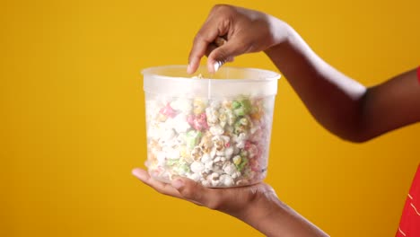 niño sosteniendo un recipiente de palomitas de maíz coloridas