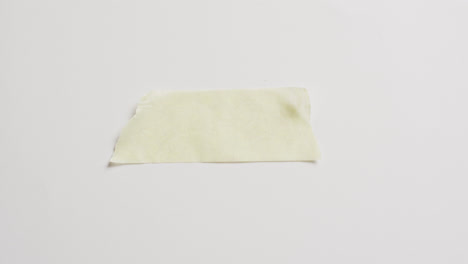 video of close up of torn piece of yellow paper on white background