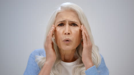 Senior-woman-worrying-about-health-inside.-Shocked-lady-opening-mouth-indoor.