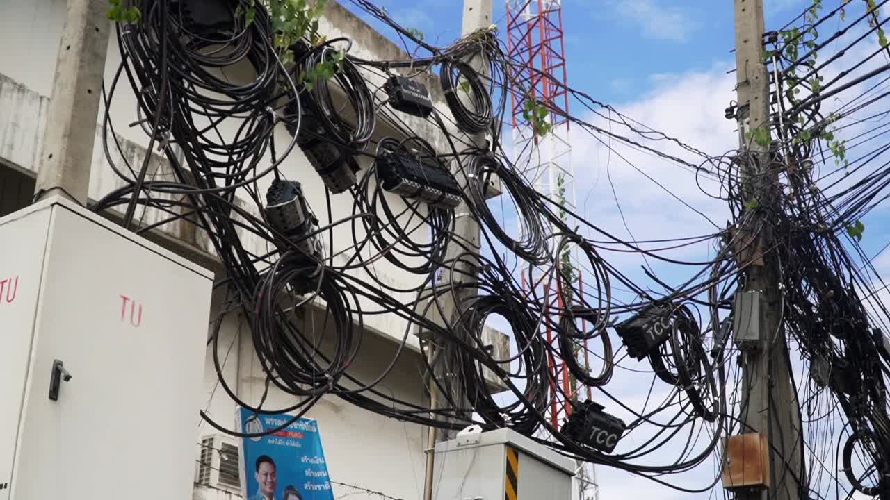 Messy Electric Wires and Telephone Cables Over The City Streets Of Bangkok Thailand