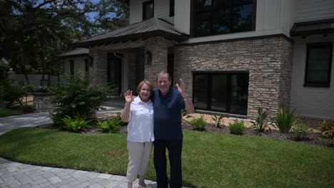 happy senior citizen couple smiling and waving in front of the house as if they are pleased with services