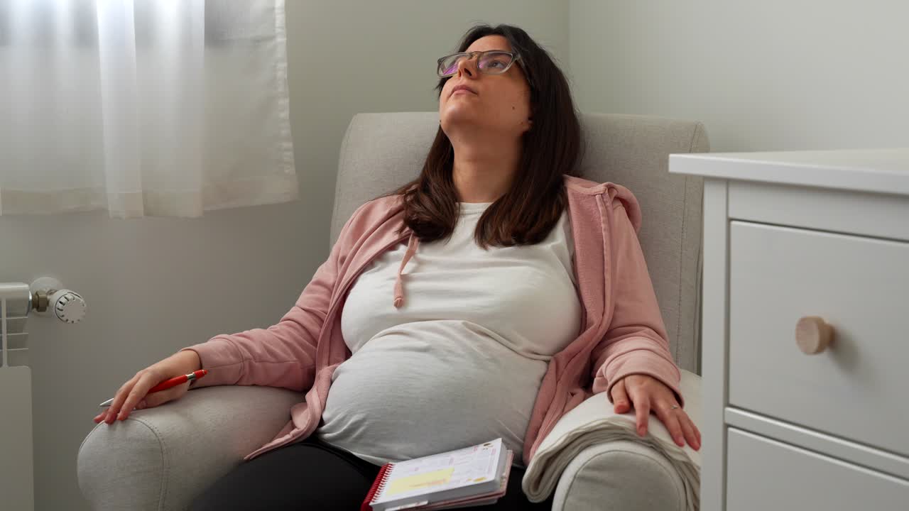 Pregnant woman in a rocking chair doing a final check of her hospital checklist