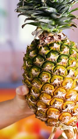 hands presenting a pineapple in a kitchen