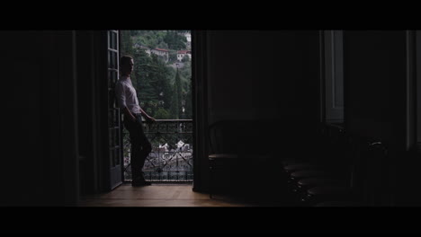 man looking out a balcony window with a view