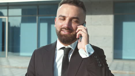 hombre de negocios hablando por teléfono fuera del edificio de oficinas