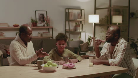 black men and boy having fun while eating at home