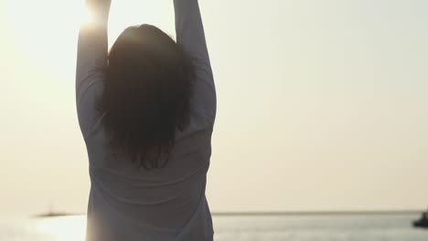una mujer disfrutando de una puesta de sol junto al océano.