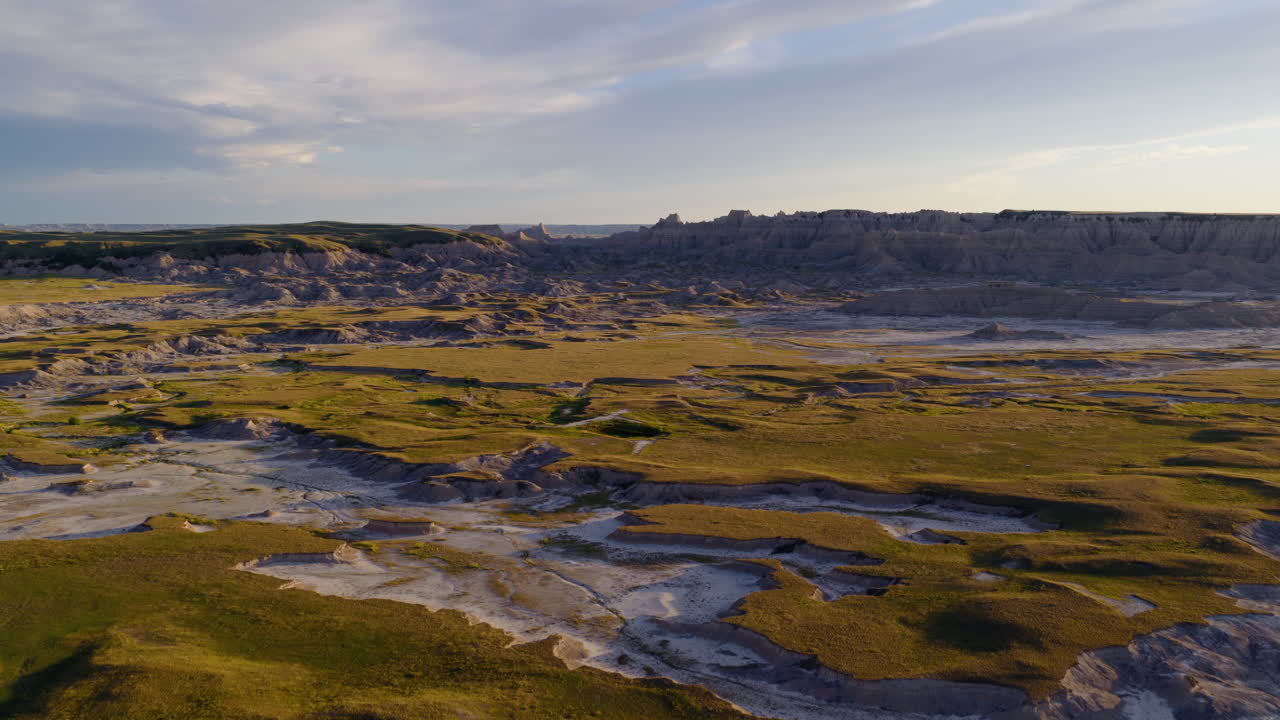 Soaring Over Rugged Badlands Terrain as the Sun Sets in Warm Hues