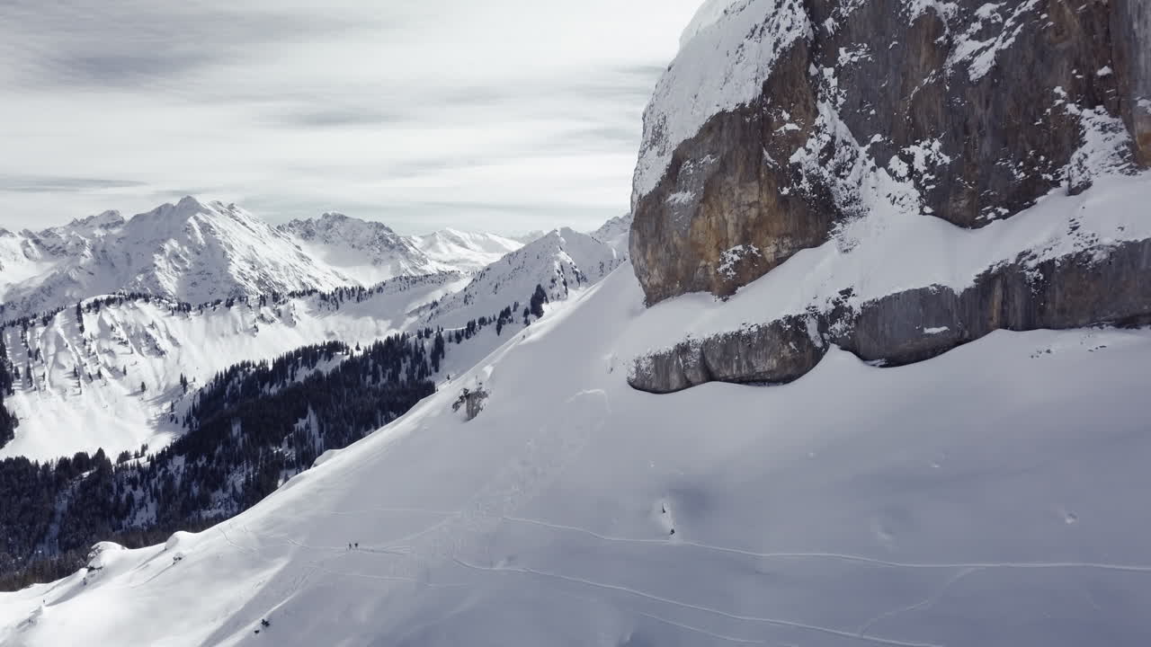 Riprese aeree con drone di una roccia di montagna nelle Alpi, Austria, Kleinwalsertal, area sciistica, montagne innevate.