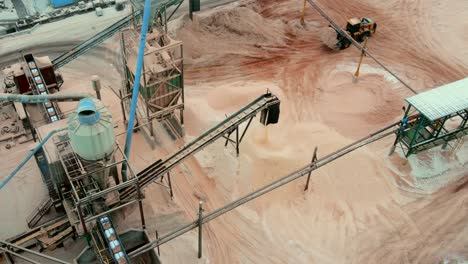 wheel loader in action at sawmill: moving sawdust away from piles created by conveyor belt system in plywood production