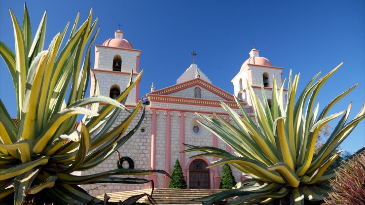 Chiesa della storica Missione Cattolica Spagnola di Santa Barbara in California, con piante e cieli blu SCORRI A DESTRA