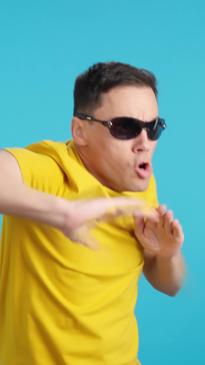 Man dancing in yellow shirt and sunglasses