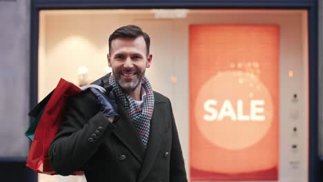 retrato de un hombre sonriente con bolsas de compras en el tiempo de navidad