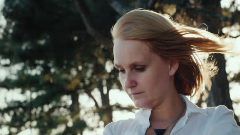 portrait of a woman in a pine forest with the wind blowing into her hair 3