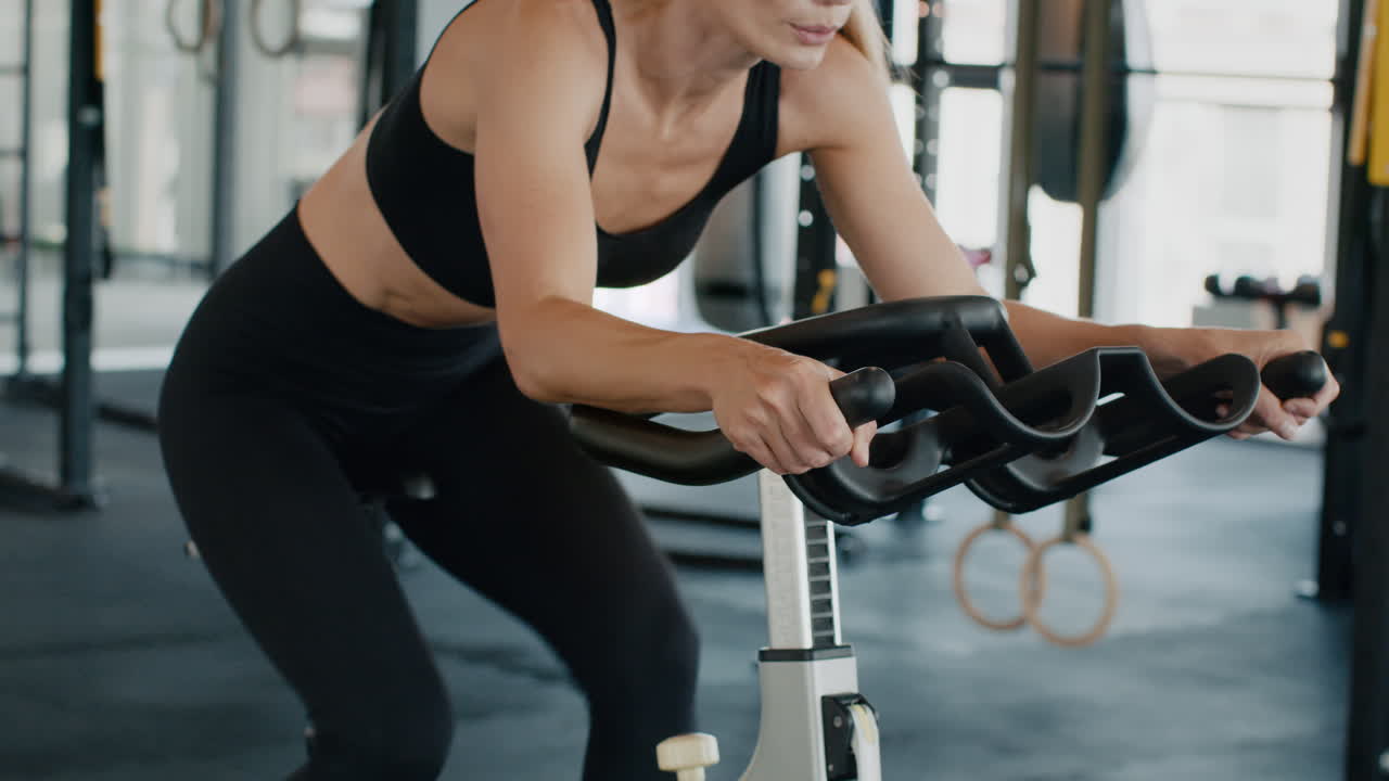 체육관 에서 회전 자전거 를 타고 운동 하는 여자