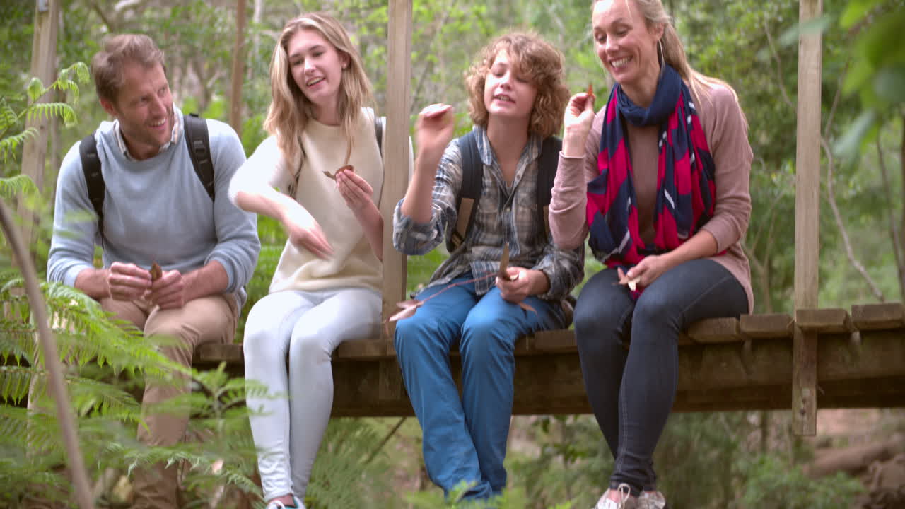 familia sentada en un puente de madera jugando en un bosque