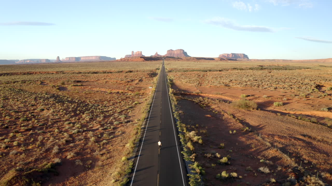 유타의 빈 숲 검프 고속도로를 따라 모뉴먼트 밸리를 걷는 남자의 공중 드론 영상