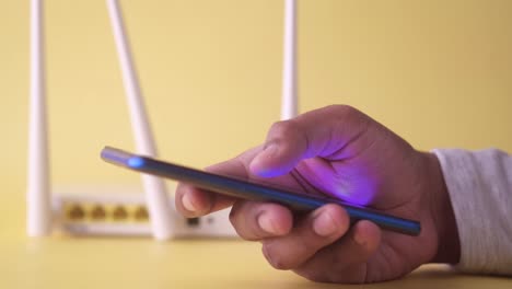 persona que utiliza un teléfono inteligente cerca de un enrutador