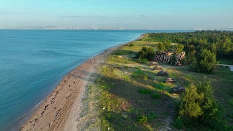 Aerial-birds-eye-shot-over-green-island-of-Kinmen,-金門,-Quemoy-with-sandy-beach-and-anti-landing-barriers---China-in-background---War-between-Taiwan-and-China