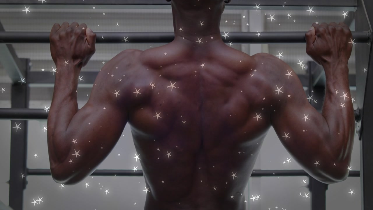 Man gripping pull-up bar and pulling up in gym, star-like particles highlighting fitness training
