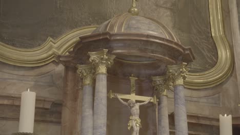 camera pans to a crucifix in a baroque altar, between two candles