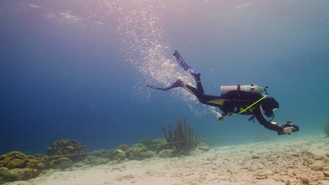 Scuba-Diver-Jugando-Con-Scooter-Submarino-Sobre-Suelo-Arenoso